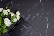 Bible on a black marble desk with white roses 