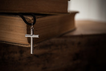 cross necklace and stack of books 