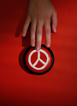 a child's hand on a peace button 