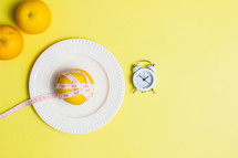 Diet concept with oranges and clock over the yellow background. 