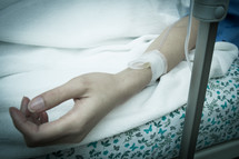 arm with an iv in a hospital bed 
