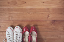 red dress shoes and sneakers on a wooden floor 
