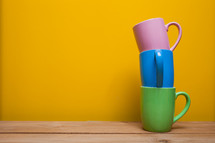 stacked mugs against a yellow wall 