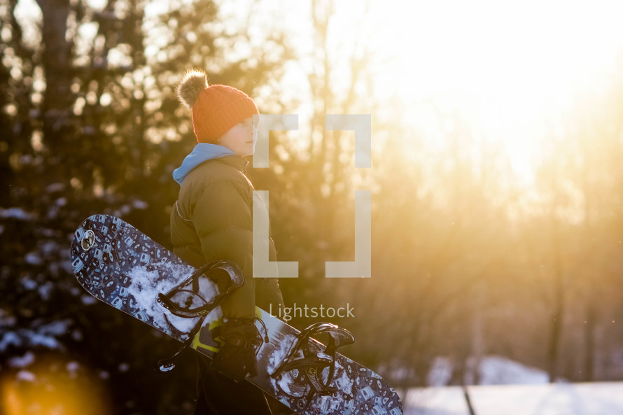 a boy carrying a snowboard 
