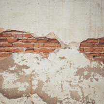 exposed brick under a plastered wall 