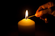 lighting a candle with a match 