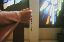 A woman kneeling and praying the rosary in a Catholic church