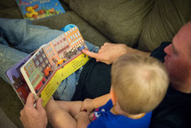 father and toddler son reading a book