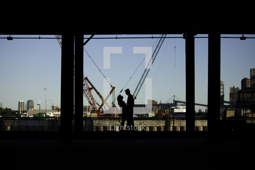 silhouette of a couple standing under an overpass 