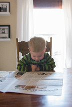 toddler boy reading a newspaper 