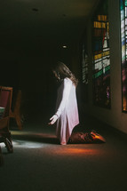 A young woman praying in the back of a Church on her knees 