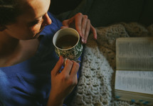 woman under blankets reading a Bible 