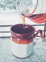 pouring coffee into a mug outdoors in snow 