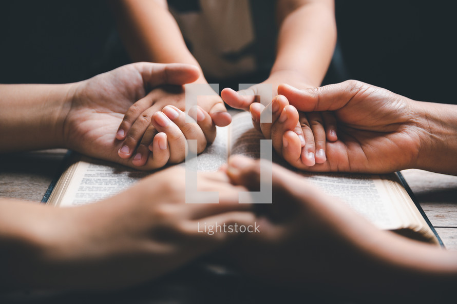 Family praying on a Bible