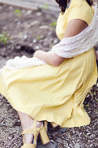 A young woman in a yellow dress, sitting down.