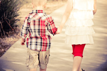 Little brother & big sister holding hands walking