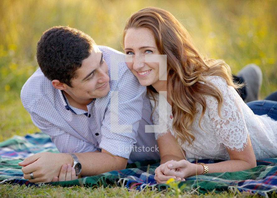 couple lying on  a blanket outdoors 
