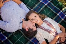 couple lying on a blanket together outdoors 