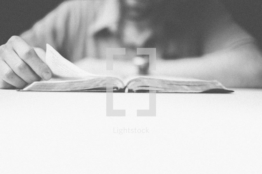 Man reading an open Bible on a table.