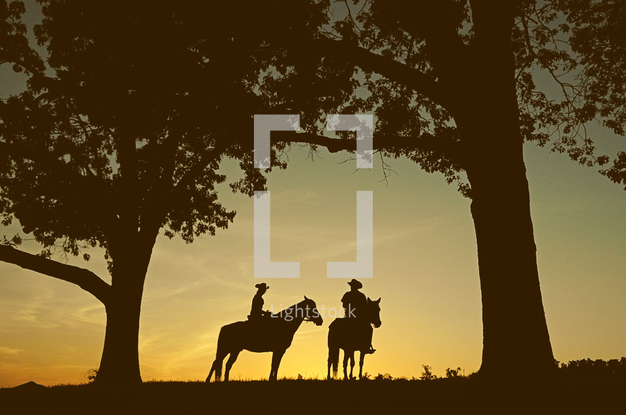 silhouettes of cowboys on horses 