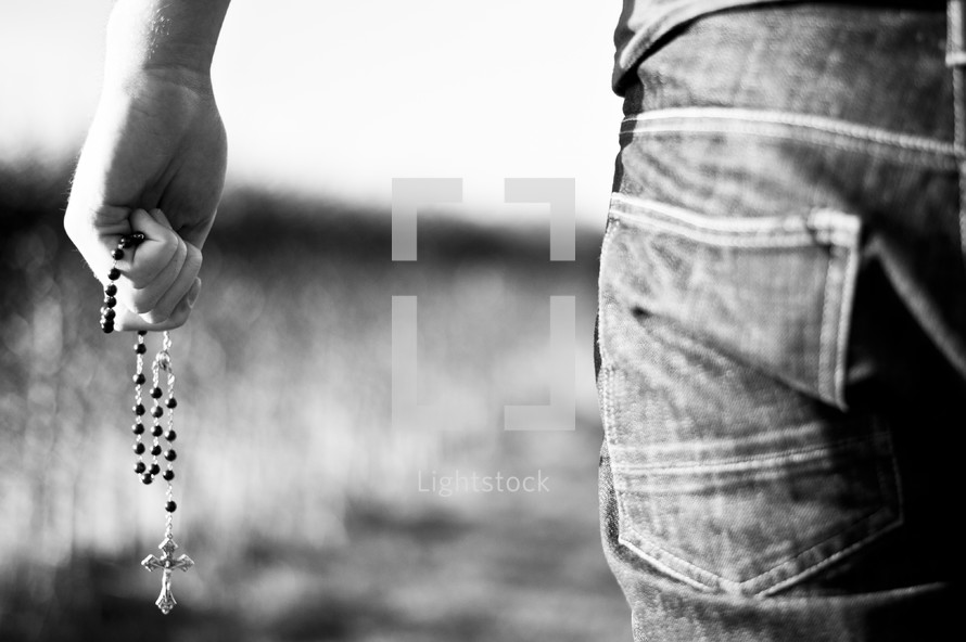 man holding a rosary at his side