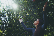 woman standing outdoors with raised hands of worship 