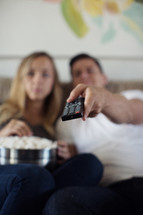 a couple watching a tv movie, remote control and popcorn 