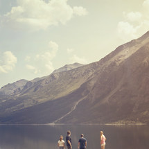 people standing on a mountain lake shore 