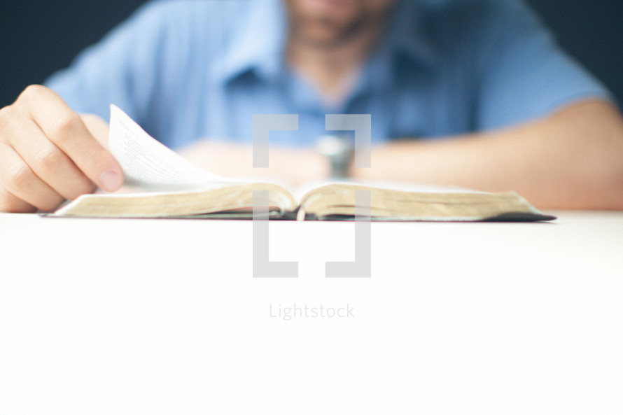 Man reading a Bible on a table.