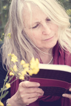 A woman reading a book outdoors.