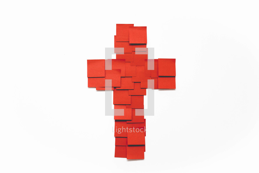A cross made of red squares of paper on a white background.