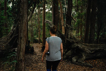 a woman with a camera walking in a forest 