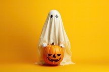 Halloween pumpkin with ghost costume on orange background. Copy space.