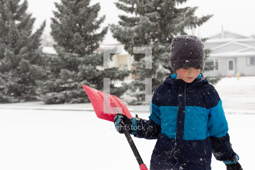 boy with a shovel in the snow 