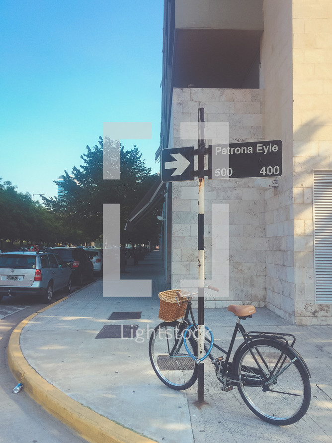 a bicycle locked on a street corner sign 