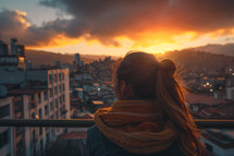 A woman looking out over a city at sunset