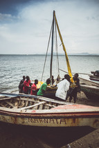 people and boats on the shore of a fishing village 