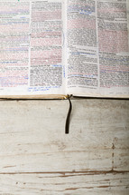 Bible open to Mark 10-11 laying on wooden table.
