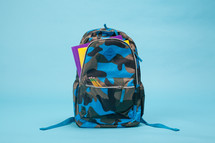Boy's camo backpack on light blue background. 
