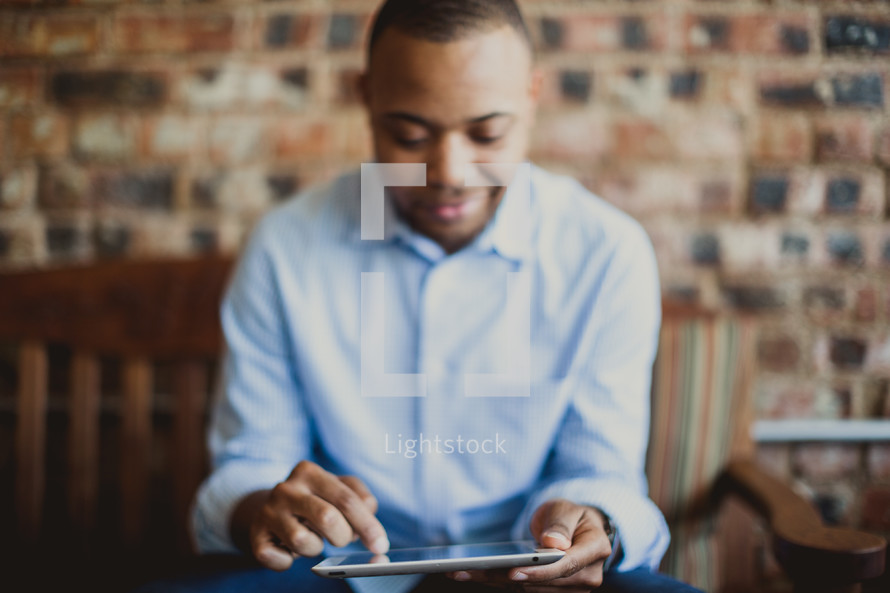 Man reading the Bible on an electronic tablet.