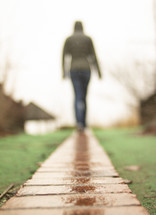 woman walking over a wet boardwalk 