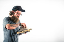 man with tattoos turning the pages of a Bible 