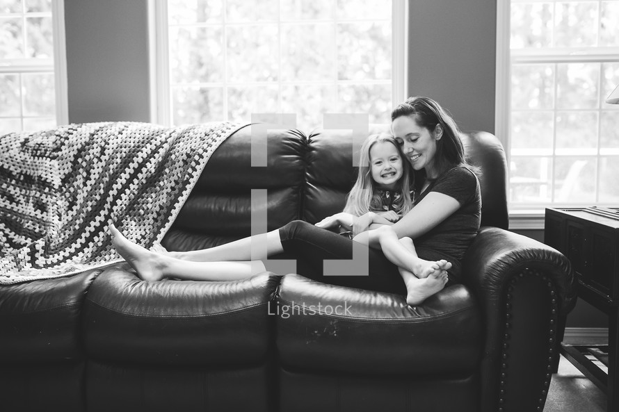 a mother and daughter snuggling on a couch 