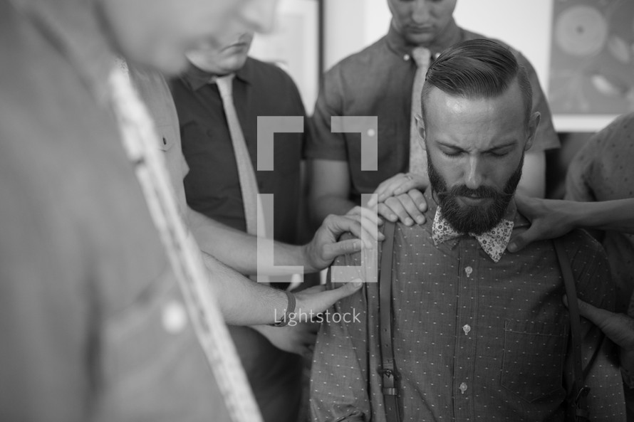 praying around a groom before a wedding 