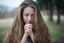 young woman outdoors in prayer 