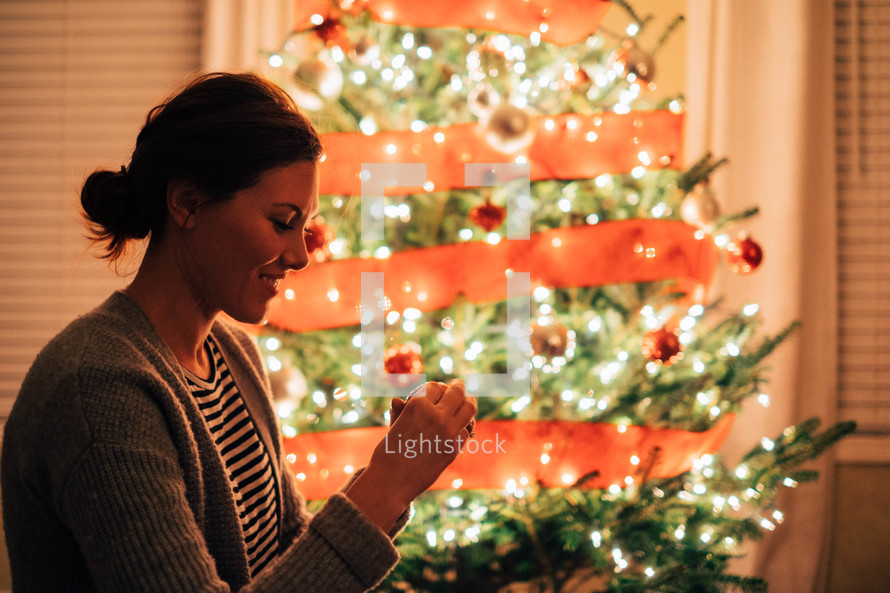 a woman decorating a Christmas tree 