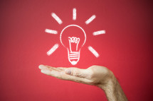 a chalk outline of a bulb "idea" supported by an outstretched hand on a red background
