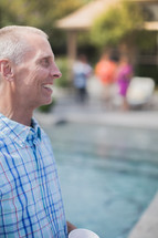 man standing by a pool at an outdoor summer party 