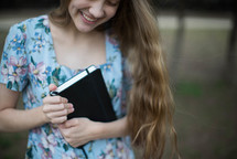 young woman holding a Bible outdoors 