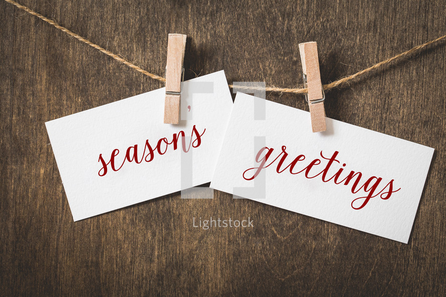 words season's greetings on white card stock hanging from a clothespin on a clothesline 